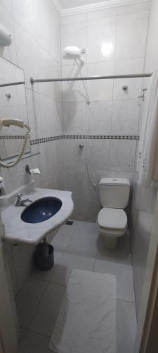 a white bathroom with a toilet and a sink at Hotel Casa Branca in Guarujá