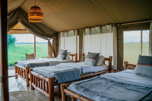 a bedroom with three beds in a tent at Zawadi Camp in Serengeti
