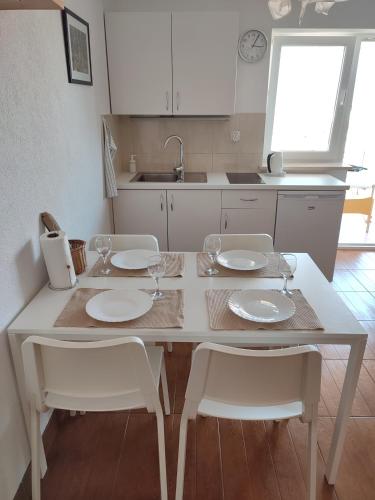 a kitchen with a table and chairs with plates and wine glasses at Apartments Filippi in Korčula