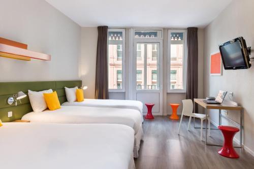 Cette chambre comprend 2 lits et une télévision. dans l'établissement Matabi Hotel Toulouse Gare by HappyCulture, à Toulouse