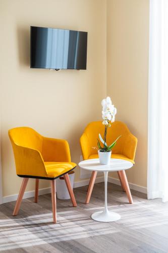 two yellow chairs and a table with a vase of flowers at Re Ottone Rooms in Lazise