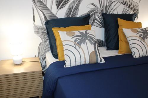 a bed with yellow and blue pillows and palm trees at Studio Ocelot - Grand studio moderne avec terrasse in Cayenne