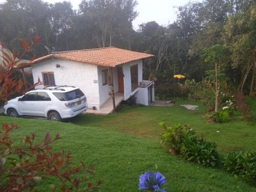 a white house with a car parked in the yard at alto palmas 2.0 in Medellín