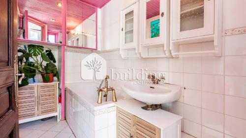 Un baño blanco con lavabo y espejo. en Master and kids bdrs separated from rest of the house, en París