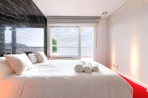 una camera da letto con un grande letto bianco con asciugamani di Derio Aeropuerto a Derio