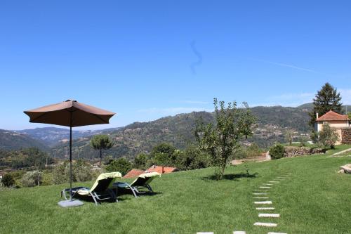 two chairs and an umbrella on top of a hill at Casa de Campo - Cinfães do Douro in Cinfães