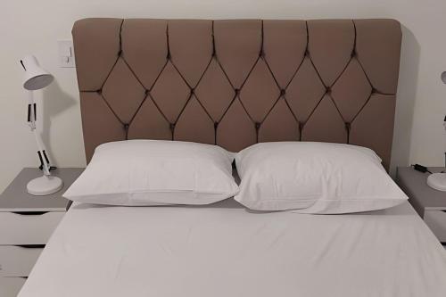 a bed with two white pillows and a brown headboard at Edifício Belluno in Ribeirão Preto