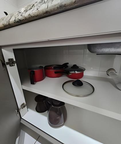 a kitchen cabinet with pots and pans on a stove at Edifício Belluno in Ribeirão Preto