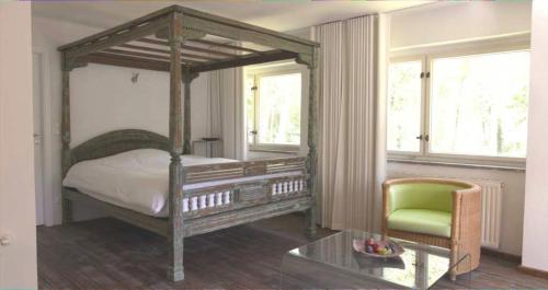 a bedroom with a canopy bed and a green chair at Park Residence Bei Wu in Wesenberg