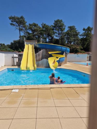 une femme et un enfant jouant sur un toboggan aquatique dans une piscine dans l'établissement Mobilhome 4/5 personnes, à Longeville-sur-Mer