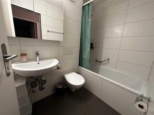 a white bathroom with a sink and a toilet at Spacious apartment in Zurich