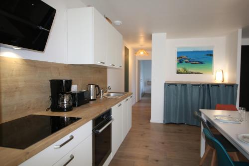 une cuisine avec des placards blancs et un comptoir dans l'établissement Maison neuve proche de la plage 3 chambres / accès PMR / Parking, à Ploemeur