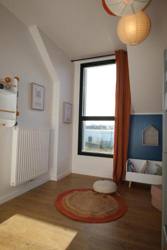a living room with a large window and a rug at Maison neuve proche de la plage 3 chambres / accès PMR / Parking in Ploemeur