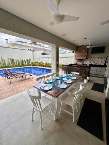 uma sala de jantar com mesa e cadeiras e uma piscina em NoMar no Guarujá