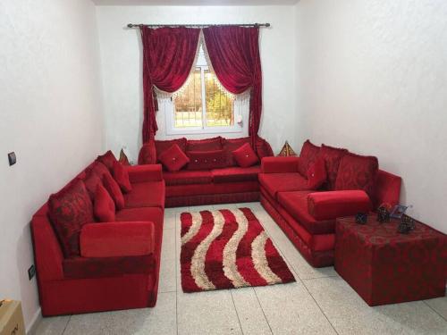 una sala de estar con sofás rojos y una ventana en Appartement une chambre, en Meknès