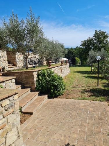 a stone retaining wall with stairs and trees in a field at OLEA casa vacanze in Todi