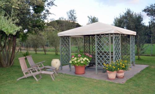 a gazebo with a chair and flowers in a yard at Agriturismo la Ghiandaia Alghero in Santa Maria la Palma