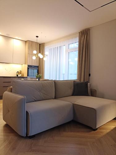 a couch in a living room with a kitchen at Apartments with a balcony and an impressive terrace on the roof of the house - PRIVATE FREE CAR PARKING in Vilnius