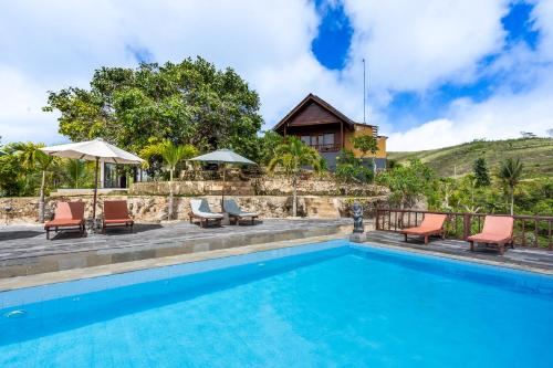 a swimming pool with chairs and a house at Pini Sentana Village Nusa Penida in Nusa Penida