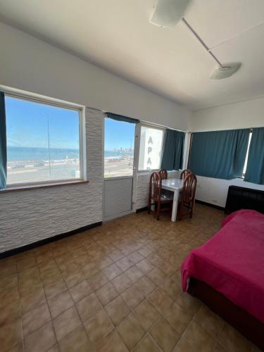 a bedroom with a bed and a table and some windows at La PerlaApart in Mar del Plata