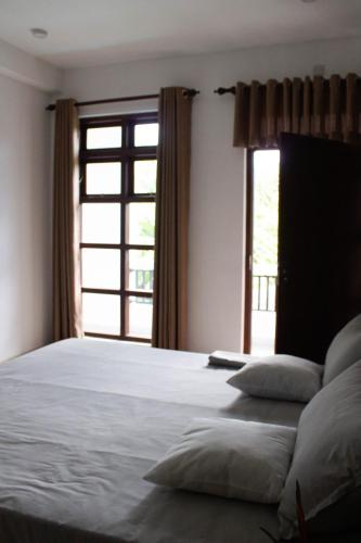 a bedroom with a large bed with a window at URALSURF HOUSE in Weligama