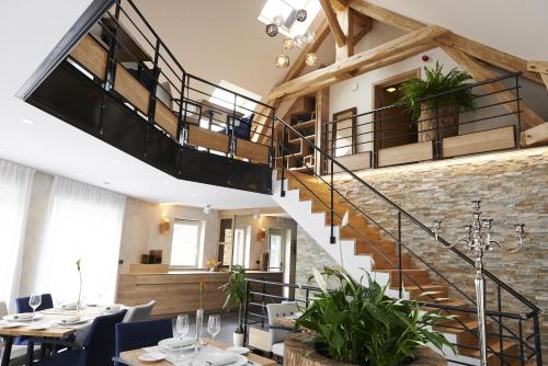 a restaurant with a staircase and tables and chairs at Koru Hôtel & Private Wellness in Autre-Église