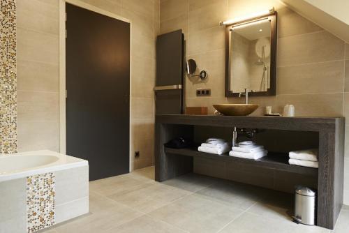 a bathroom with a sink and a tub and a mirror at Koru Hôtel & Private Wellness in Autre-Église