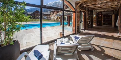 une terrasse avec des chaises blanches et une piscine dans l'établissement Les alpages location appartement 108, à Lanslebourg-Mont-Cenis