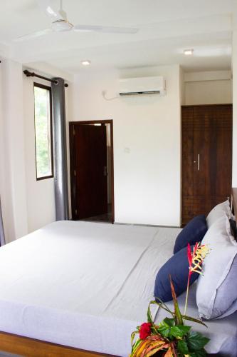 a bedroom with a large white bed with blue pillows at URALSURF HOUSE in Weligama