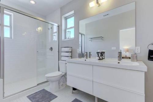 a white bathroom with a toilet and a large mirror at Bridge - A Birdy Vacation Rental in San Antonio