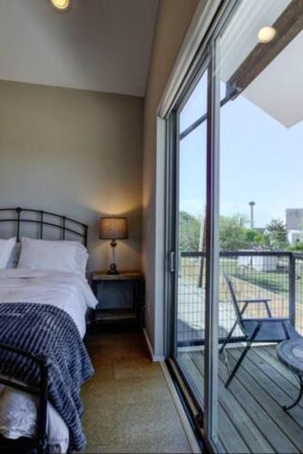 a bedroom with a bed and a balcony with a sliding glass door at Bridge - A Birdy Vacation Rental in San Antonio