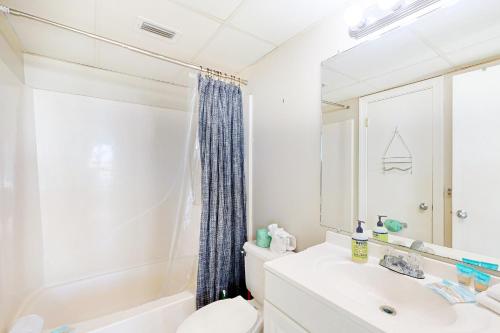 a bathroom with a sink and a toilet and a mirror at Sunbird #408E in Panama City Beach