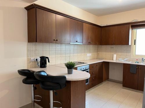a kitchen with wooden cabinets and a counter with stools at Coastal Elegance Maisonette in Limassol