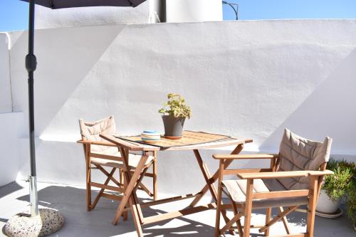 einen Tisch und Stühle mit einer Topfpflanze auf einer Terrasse in der Unterkunft Chora Cozy Studios in Kythnos