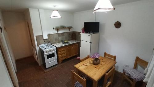 a kitchen with a stove and a refrigerator and a table at Casita de Montaña in Cosquín