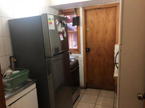 uma cozinha com um frigorífico preto e uma porta de madeira em Cabaña Haywood em Puerto Varas