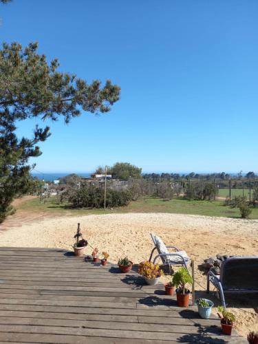 una terraza de madera con sillas y macetas en la playa en Casa Campo Mar Mirasol en Algarrobo
