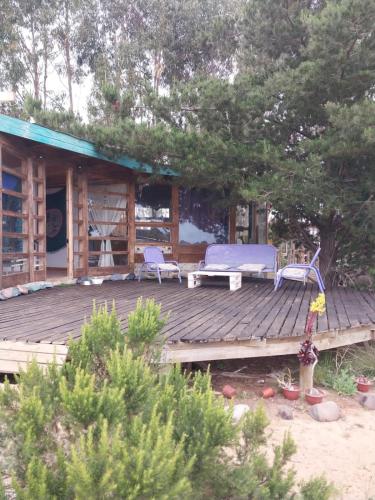 een houten terras met twee stoelen en een huis bij Casa Campo Mar Mirasol in Algarrobo