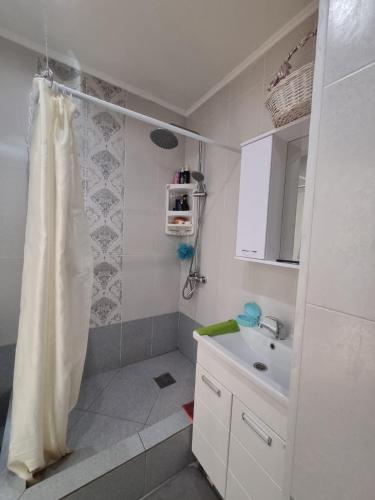 a white bathroom with a shower and a sink at Уютная квартира в сердце правого берега in Astana