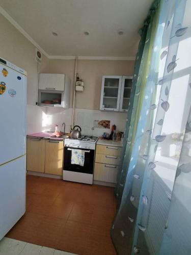 a kitchen with a stove and a white refrigerator at Уютная квартира в сердце правого берега in Astana