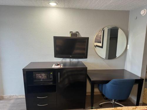 a room with a desk with a television and a mirror at Midtown Lodge in Jacksonville