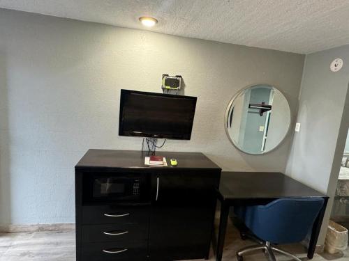 a room with a desk with a television and a mirror at Midtown Lodge in Jacksonville