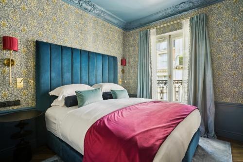 une chambre avec un grand lit avec une tête de lit bleue dans l'établissement Séjours Parisiens - Suites Haussmann, Malesherbes & Madeleine, à Paris