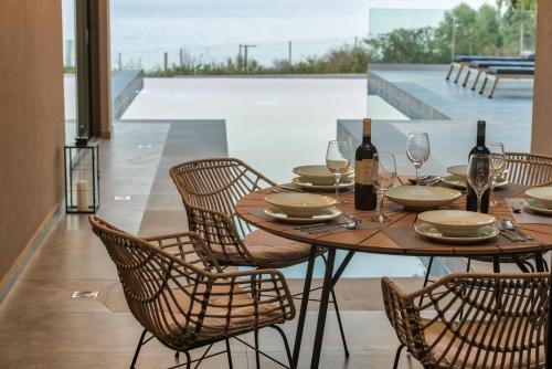 a wooden table with chairs and wine bottles and glasses at Luxury Villa Mon I Vassilikos in Vasilikos