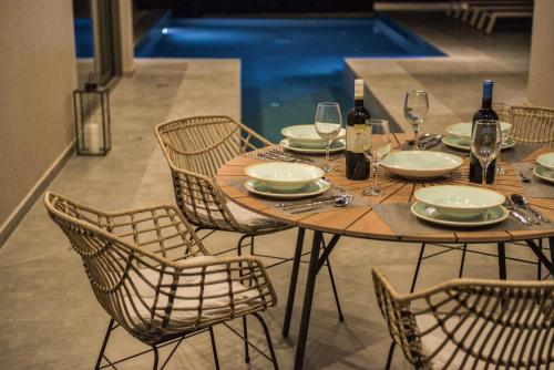 a wooden table with chairs and wine bottles and glasses at Luxury Villa Mon I Vassilikos in Vasilikos