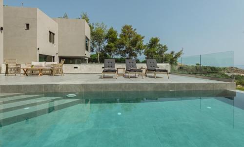 a swimming pool with chairs and a table next to a house at Luxury Villa Mon II Vassilikos in Vasilikos