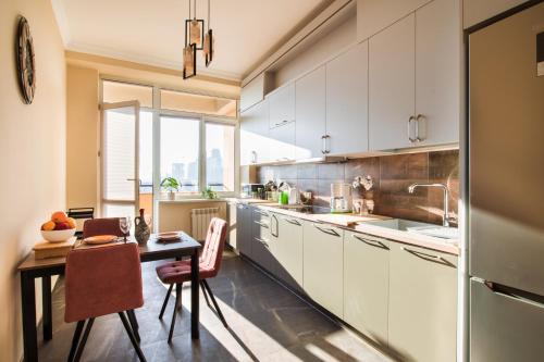 a kitchen with white cabinets and a table with chairs at hotelise l Riverview Apartment in Yerevan
