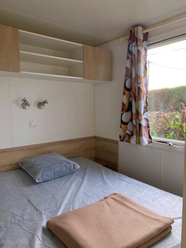 une petite chambre avec un lit et une fenêtre dans l'établissement Mobil-home mitoyen 1 chambre, à Angicourt