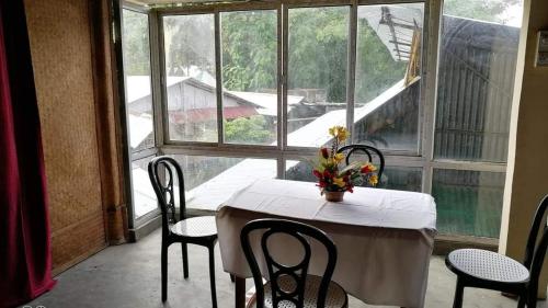 einen Tisch und Stühle in einem Zimmer mit einem großen Fenster in der Unterkunft Ashrayaa Prakreeti. in Jorhat