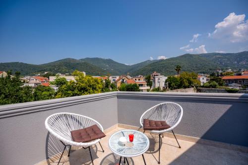 two chairs and a table on a balcony with mountains at Miro guesthouse in Tivat